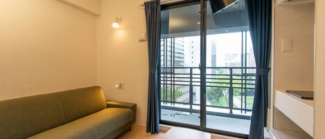 A modern living room with a sofa, a table with a box, and a large window with curtains.