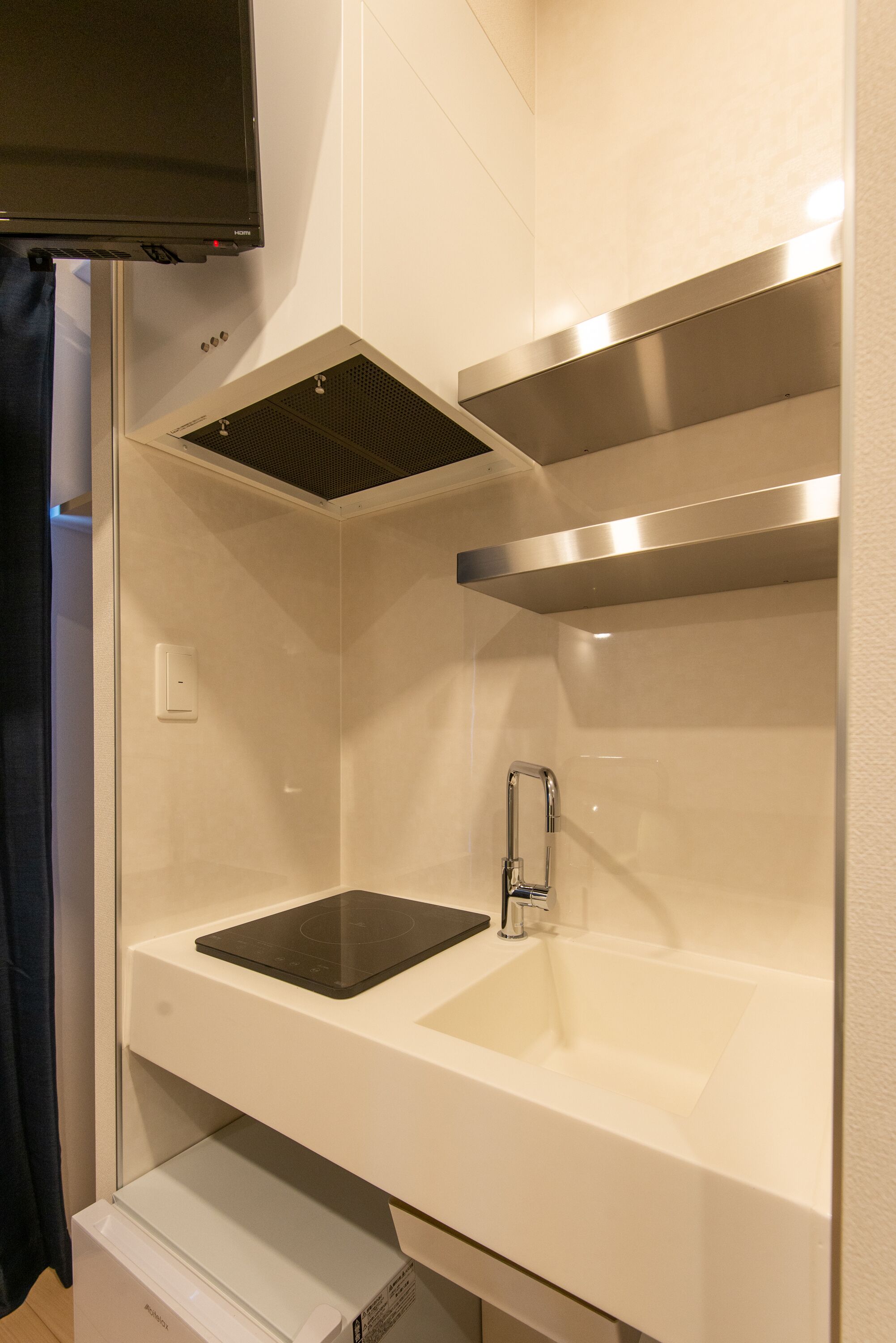 Un baño moderno con lavamanos integrado, un espejo y sistema de ventilación.