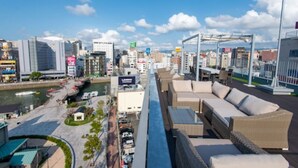 Un paisaje urbano moderno con rascacielos, un paseo marítimo y zonas de estar al aire libre.