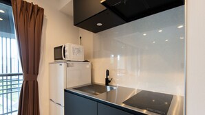Una kitchenette compacta con microondas, refrigerador y estufa moderna.