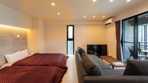 Una habitación de hotel moderna con dos camas, un sofá, un televisor y un ventanal grande.