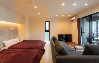 Ein modernes Hotelzimmer mit zwei Betten, einer Couch, einem Fernseher und einem großen Fenster.