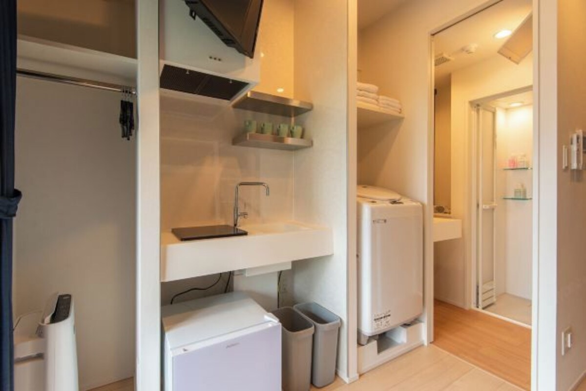 A compact kitchen with white appliances, a built-in sink, and a small countertop with shelves.