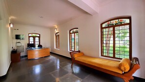 A reception area with a wooden bench, a desk, and a television. There are large windows with decorative glass panes. - Avadale Masinagudi - Stag Groups Not Allowed  (Ootacamund)