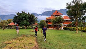 A grassy field with a building in the background. - Avadale Masinagudi - Stag Groups Not Allowed  (Ootacamund)