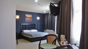 Ein Hotelzimmer mit einem Bett, einem Sessel, einem Tisch mit Lampe und einem Fernseher.