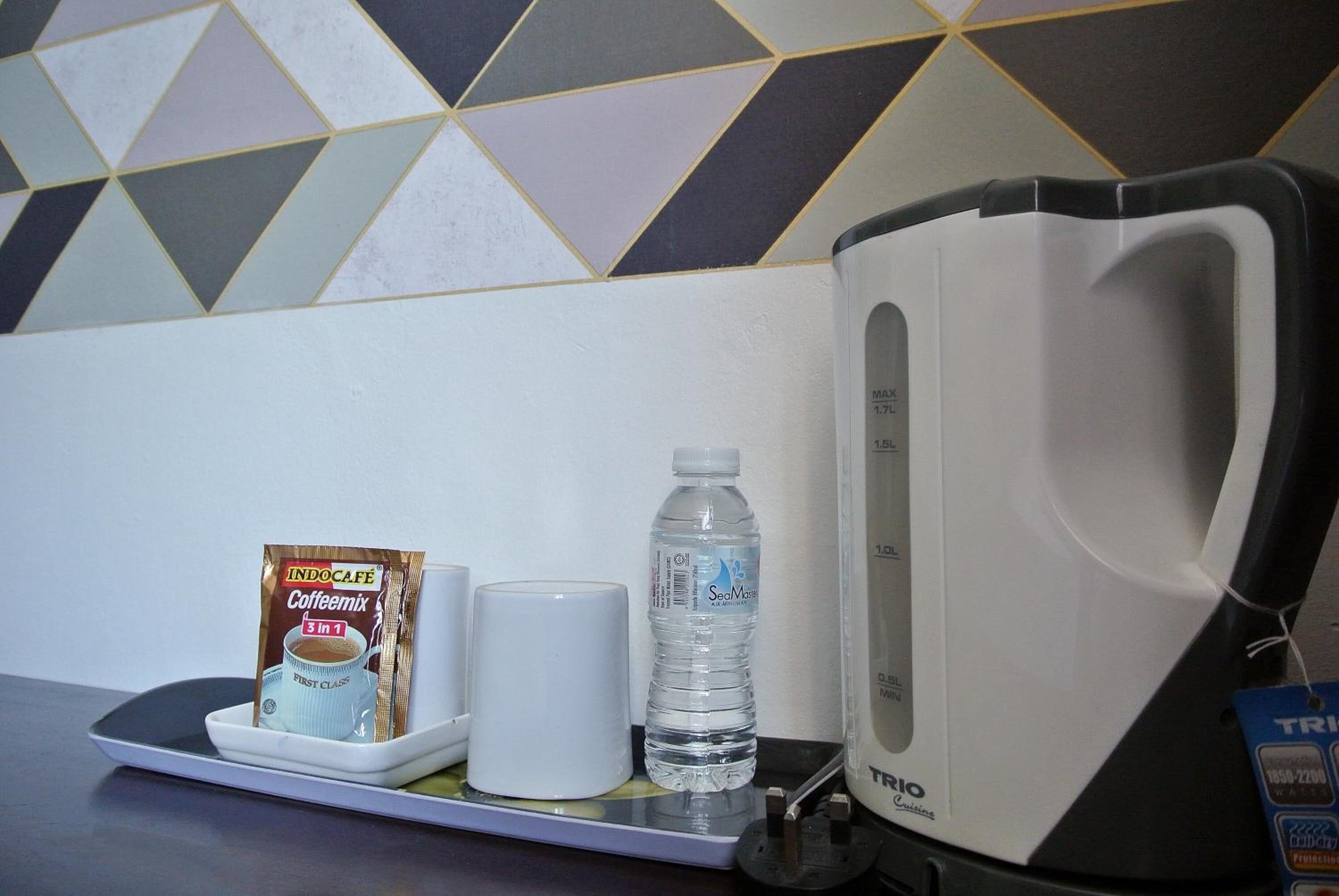 A coffee maker, a water bottle, and a packet of coffee mix on a scale.