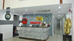Ein Hotelrezeptionstresen mit einem 'Hotel 88'-Schild, einem Rauchverbotsschild, einem Schild für kostenloses WLAN und einer dekorativen Wanduhr.