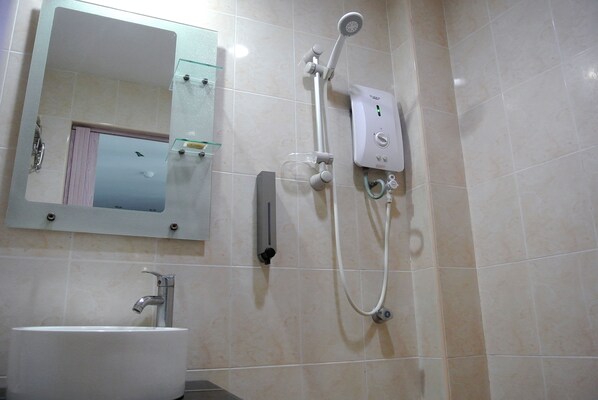 A bathroom with a sink, mirror, and a wall-mounted shower unit. - Hotel88 (Chukai)