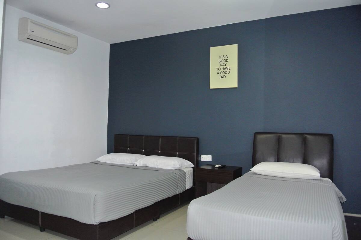 A hotel room with two beds, a wall-mounted air conditioner, and a motivational poster.