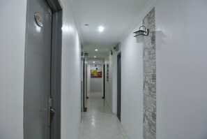 A narrow hallway with a door on the left and a wall with a cityscape mural on the right. - Hotel88 (Chukai)