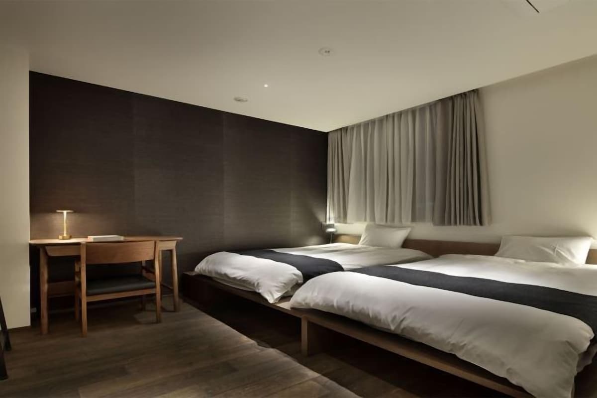 A modern hotel room with a large bed, a desk, and a dark accent wall.