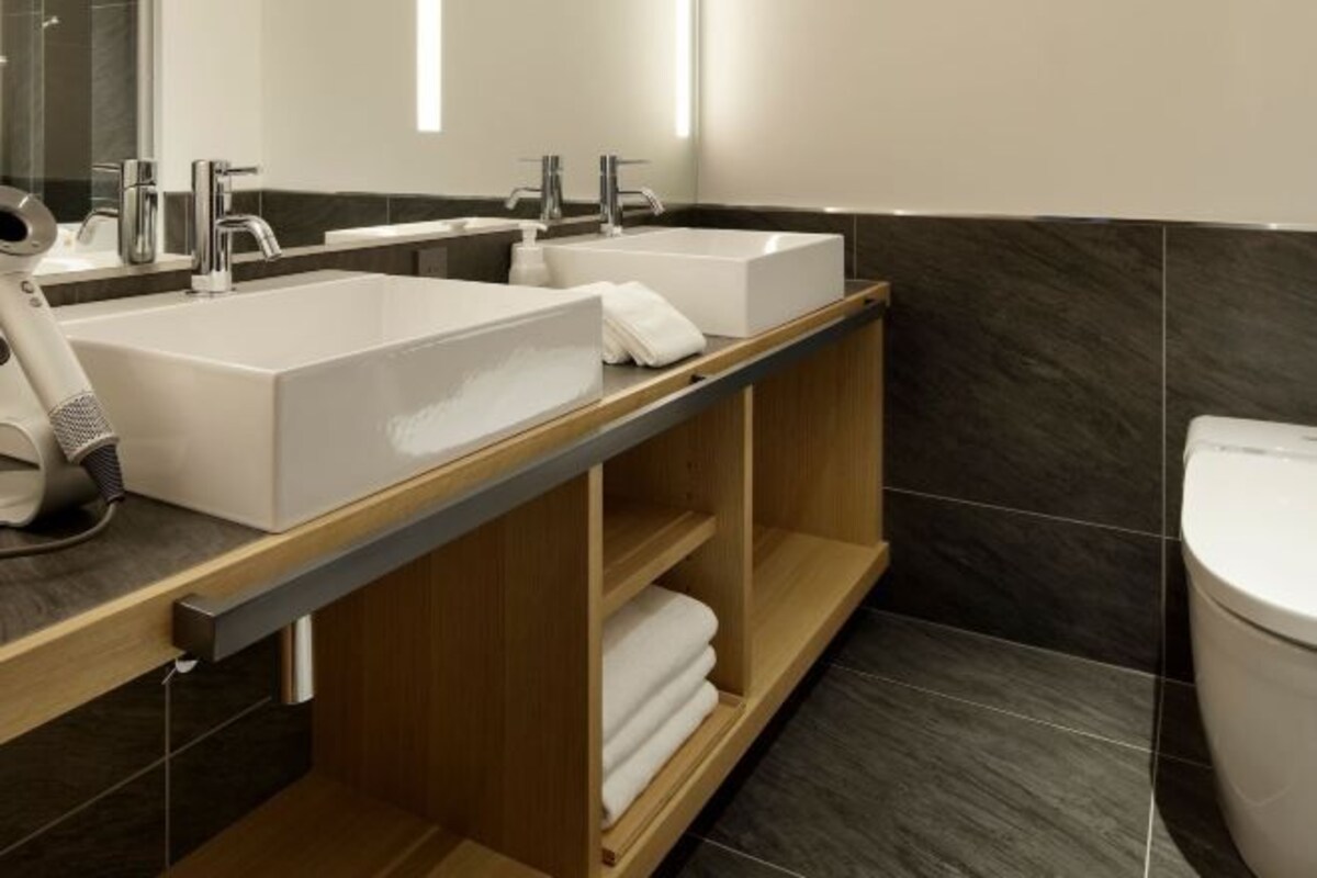 Un baño moderno con dos lavamanos, un espejo y un inodoro.