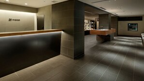 A modern hotel lobby with a reception desk, a seating area, and a kitchenette. - 20 Pieces (Kyoto)