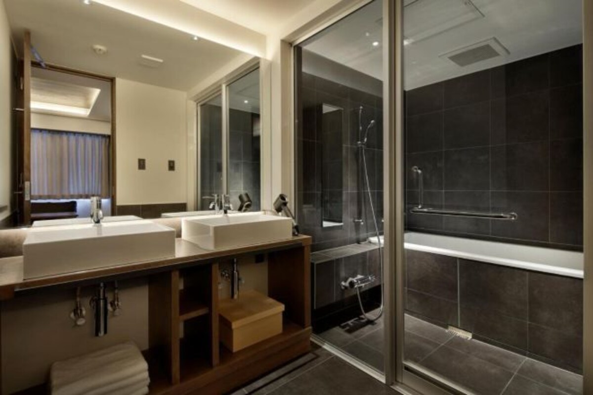 Un baño moderno con dos lavamanos, un espejo grande y cabina de ducha con paredes de cristal.