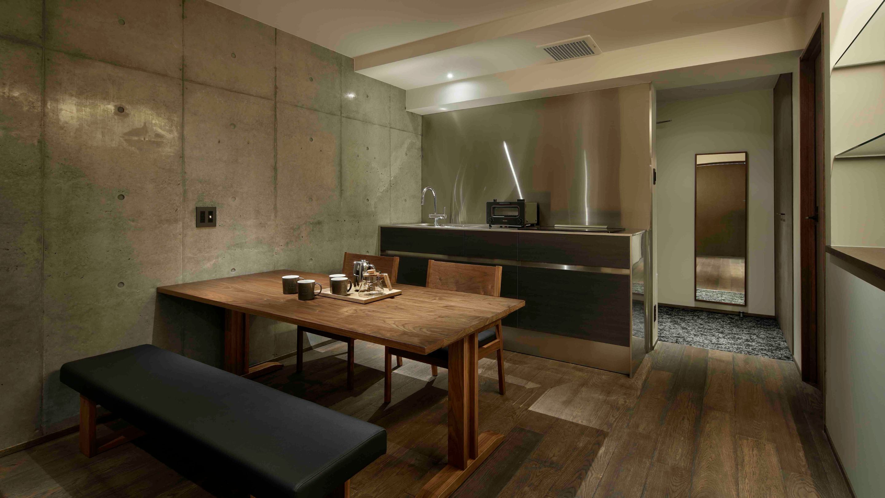 A modern kitchen with a built-in stove, a sink, and a microwave. There is a dining table with chairs and a bench.