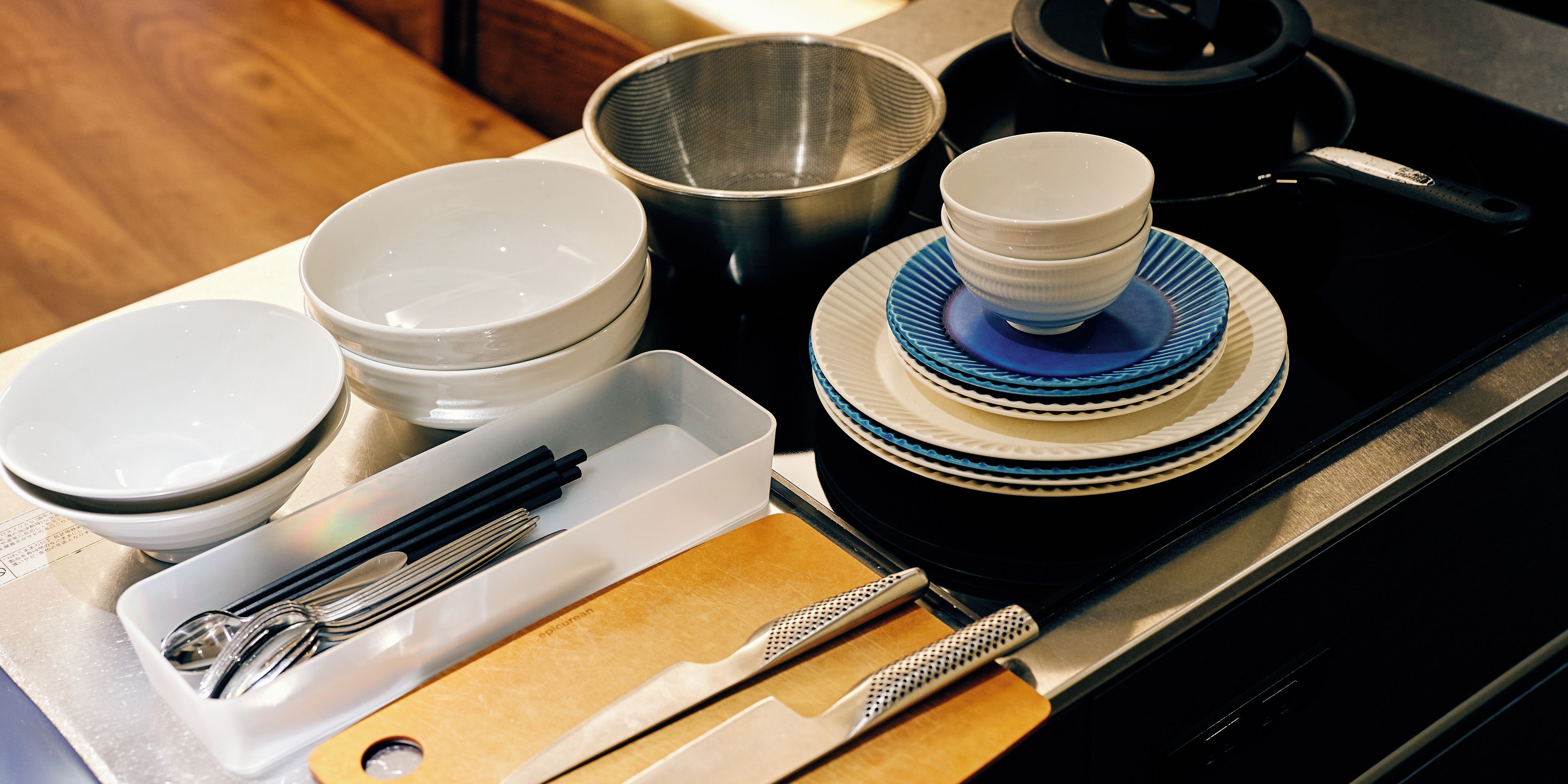 A kitchen counter with various dishes, utensils, and a tea kettle.
