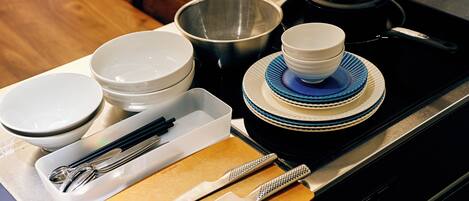 A kitchen counter with various dishes, utensils, and a tea kettle.