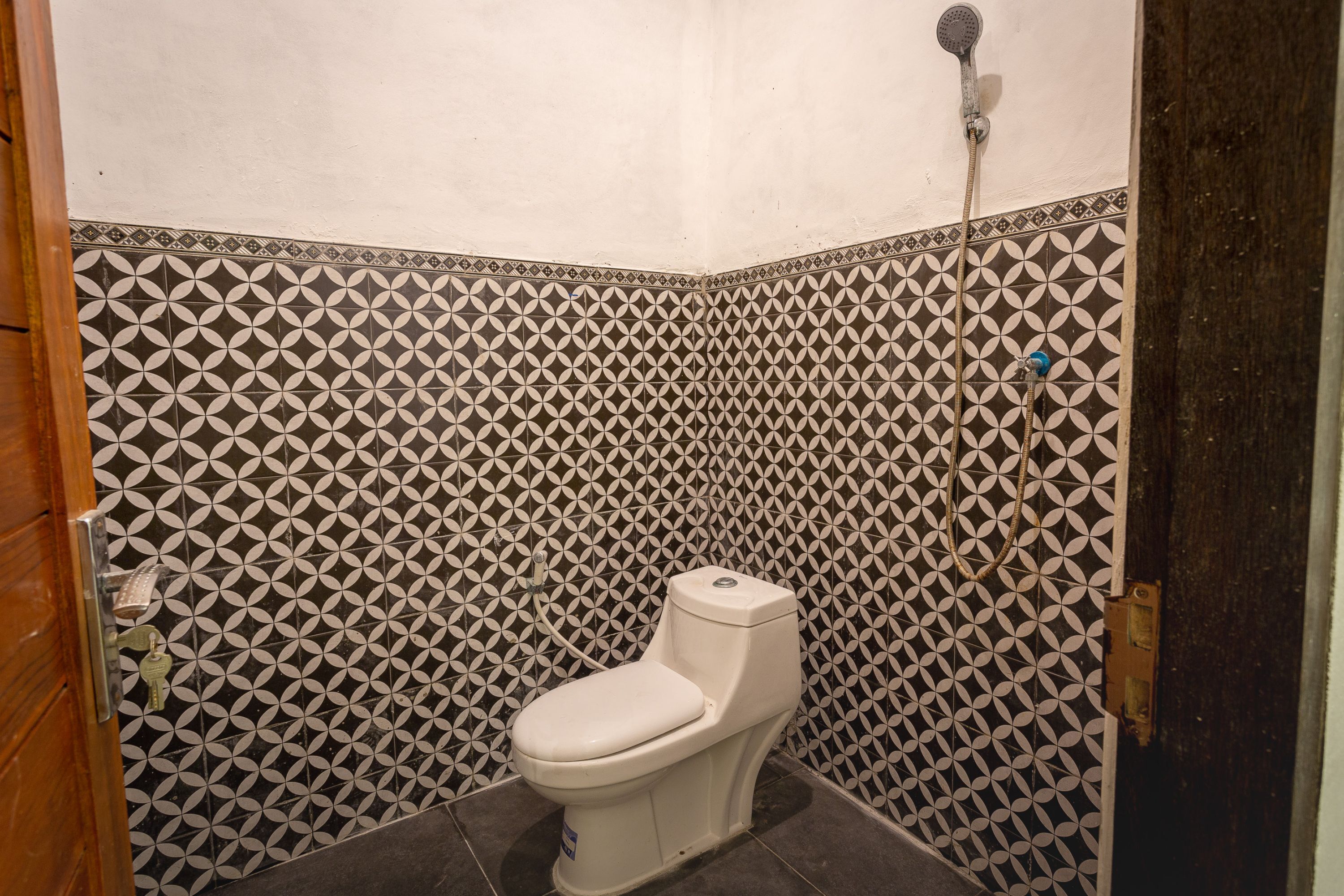 A bathroom with a white toilet, patterned tiles, and a shower.