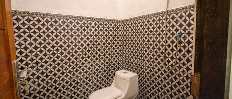 A bathroom with a white toilet, patterned tiles, and a shower.