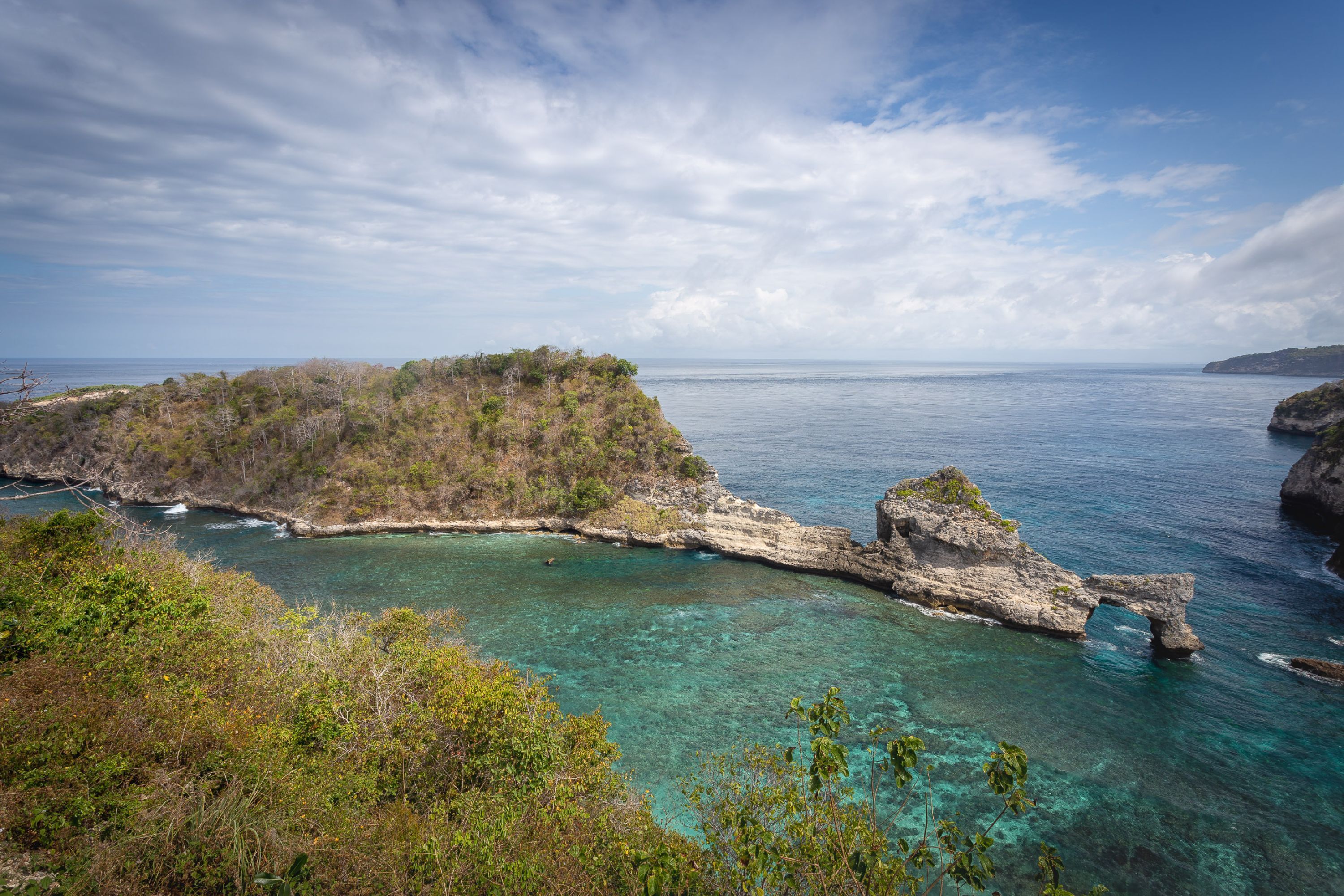 Un paysage côtier caractérisé par une eau turquoise et limpide, des formations rocheuses et une végétation luxuriante.
