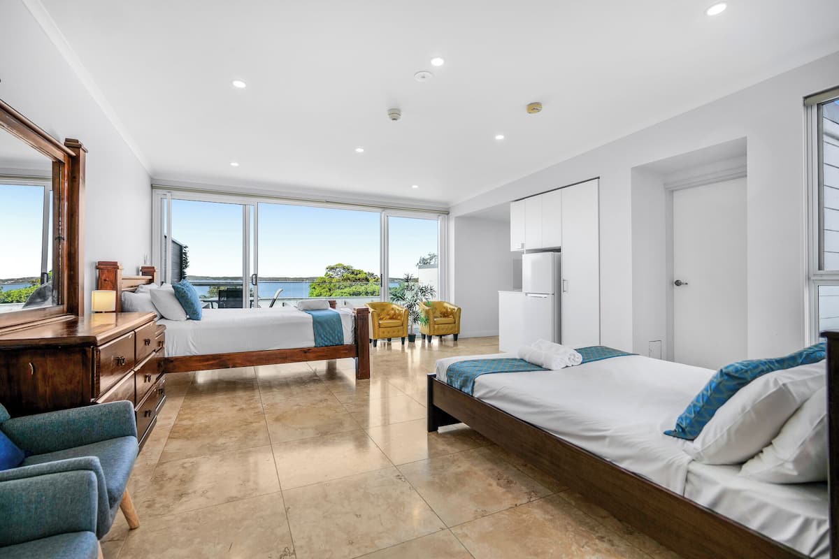 Ein modernes Schlafzimmer mit zwei Betten, einem großen Fenster und Blick ins Freie.