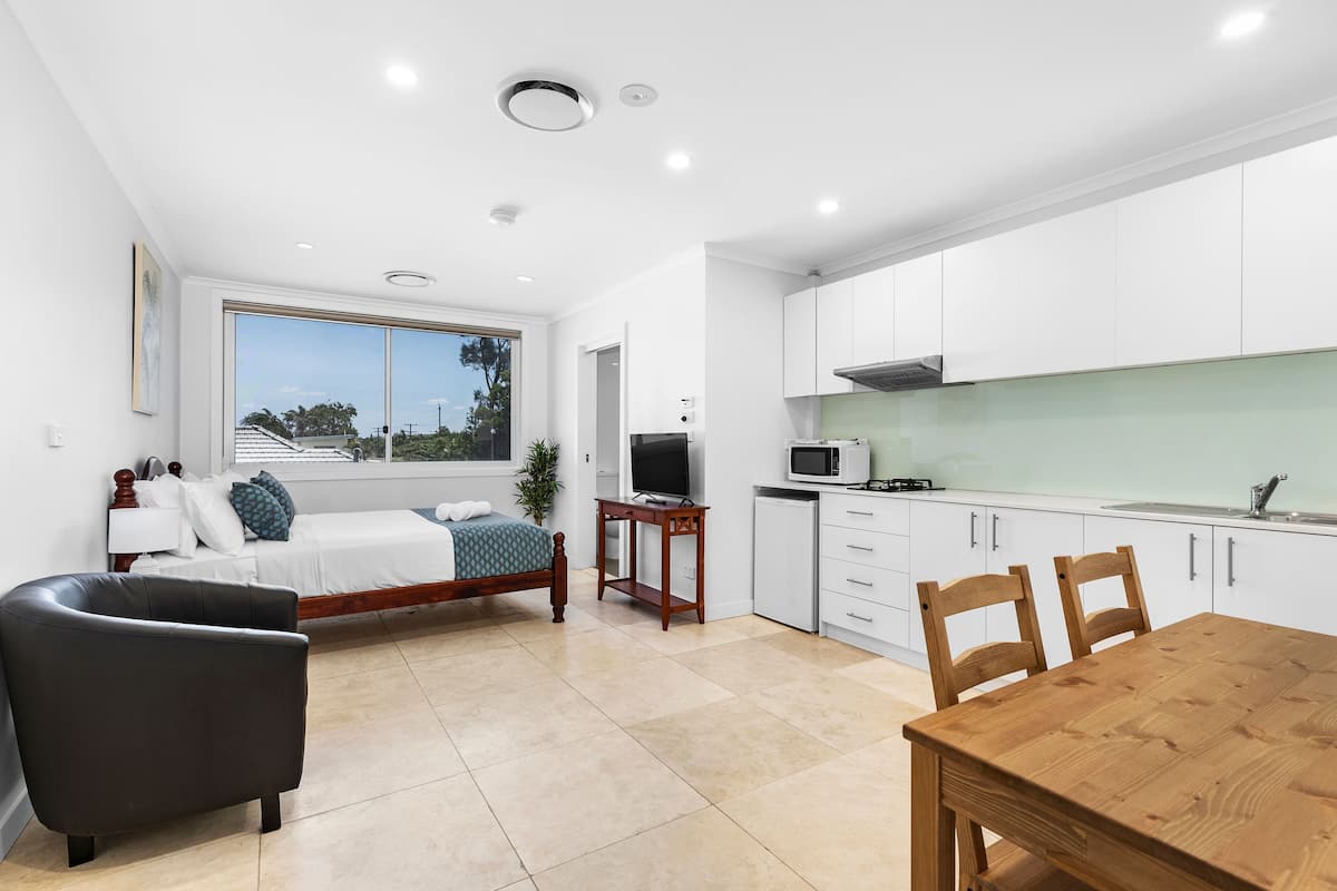 A modern kitchen with white cabinets, a dining table, and a TV.