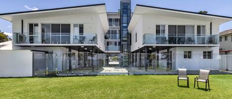 A modern two-story house with large glass windows and balconies.