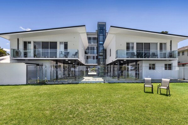 A modern two-story house with large glass windows and balconies.
