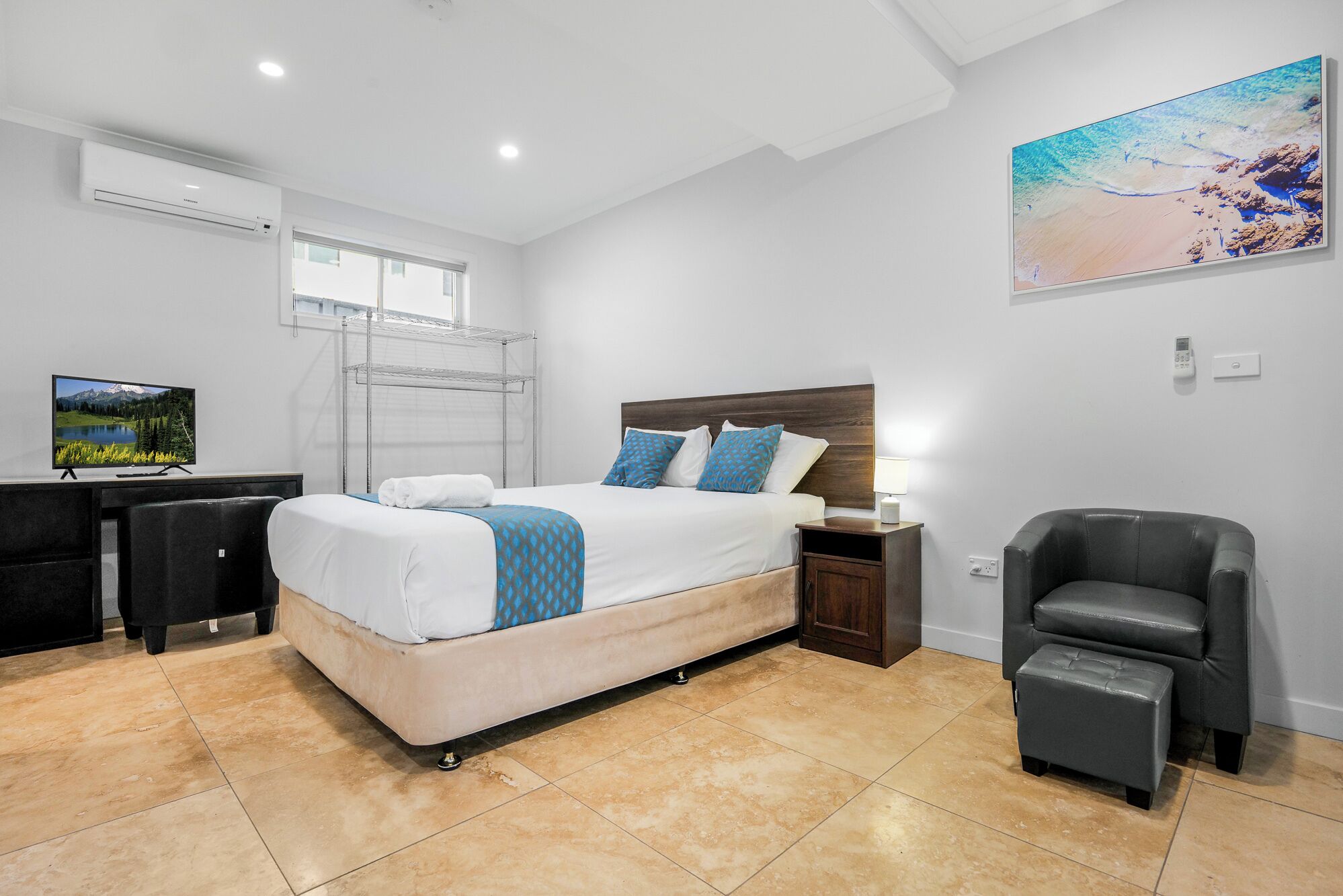 A bedroom with a bed, a desk, a chair, and a TV.