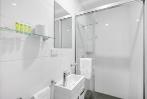 A modern bathroom with a glass shower enclosure, a white sink, and a mirror.
