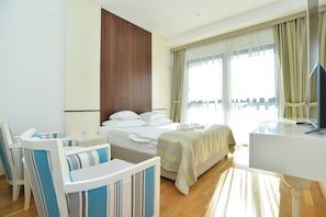A hotel room with a bed, bedside table, chair, desk, and a television. - Barbeta Accommodation (Budva)