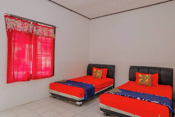 A room with two beds, each with red bedding and patterned pillows, a window with red curtains, and a tiled floor. - Spot On 1847 Hotel Maya (Beru)