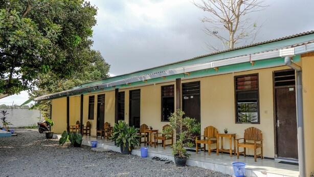 A building with a covered porch, outdoor seating, and potted plants. - Spot On 1847 Hotel Maya (Beru)