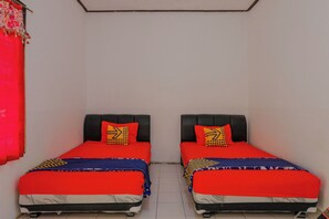 Two single beds with black headboards, red bedding, and patterned pillows in a small room with white walls and a tiled floor. - Spot On 1847 Hotel Maya (Beru)