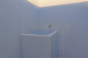 Un baño con paredes de azulejos azules y una bañera blanca.