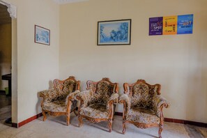 A room with three ornate chairs, a framed painting, and three colorful signs on the wall. - Spot On 1847 Hotel Maya (Beru)