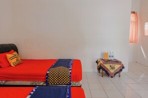 A room with a bed, a small table with a tablecloth, and a window with curtains. - Spot On 1847 Hotel Maya (Beru)