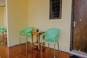 A room with two green chairs, a small wooden table, and a potted plant. - Spot On 1847 Hotel Maya (Beru)