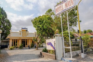 A hotel entrance with a sign for Hotel Maya, a dirt driveway, and a motorcycle parked outside. - Spot On 1847 Hotel Maya (Beru)
