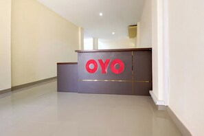 A reception area with a reception desk labeled "OYO" in red letters. - Super OYO 3092 Falah Residence Syariah (Padang)