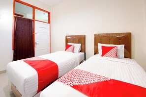 Two single beds with red and white bedding, a wooden headboard, and a white door with a mirror. - Super OYO 3092 Falah Residence Syariah (Padang)
