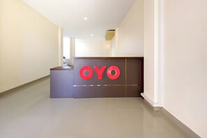 Un comptoir d’accueil arborant la marque « OYO », un intérieur propre et moderne, et un couloir droit.
