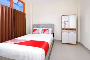 Un dormitorio con cama, armario y ventana con cortinas.