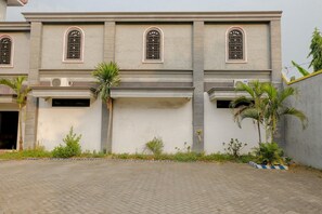Un bâtiment doté de nombreuses fenêtres, d’une cour pavée et de quelques espaces verts.
