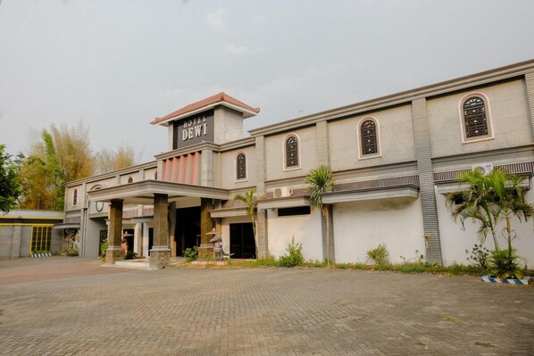 A hotel with a prominent entrance, a signboard, and a paved driveway.