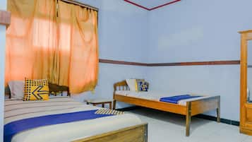 A bedroom with two beds, a wooden wardrobe, and a window with curtains.