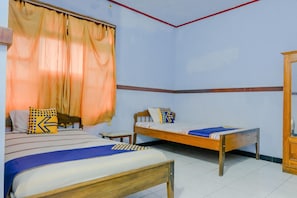 A bedroom with two beds, a wooden wardrobe, and a window with curtains. - Spot On 1971 Hotel Dewi (Peterongan)