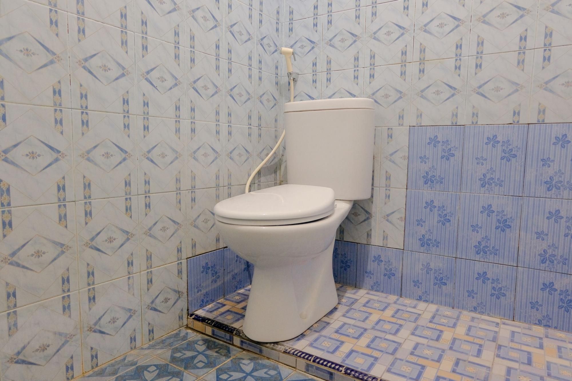 A bathroom with a toilet, patterned tiles, and a shower area.