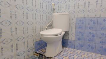 A bathroom with a toilet, patterned tiles, and a shower area.